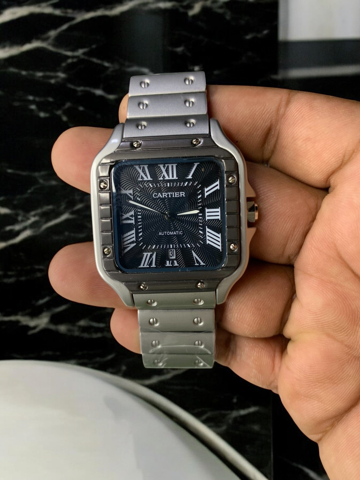 Cartier luxury watch with a sleek silver stainless steel case and bracelet, dark patterned dial, and Roman numeral markers. This automatic, 'old money' style timepiece exudes timeless elegance, perfect for luxury watch collectors and enthusiasts