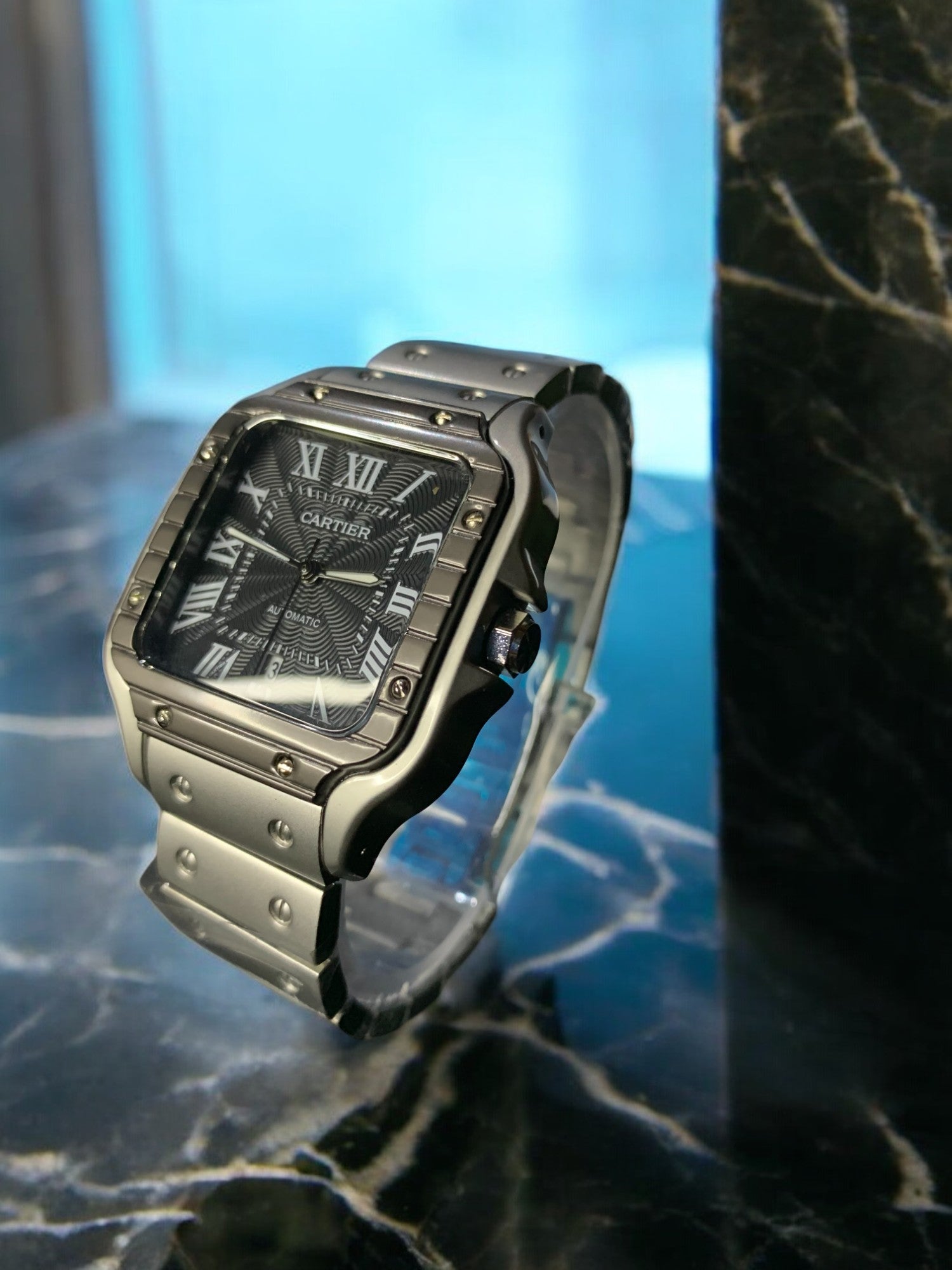 Cartier luxury watch with a sleek silver stainless steel case and bracelet, dark patterned dial, and Roman numeral markers. This automatic, 'old money' style timepiece exudes timeless elegance, perfect for luxury watch collectors and enthusiasts