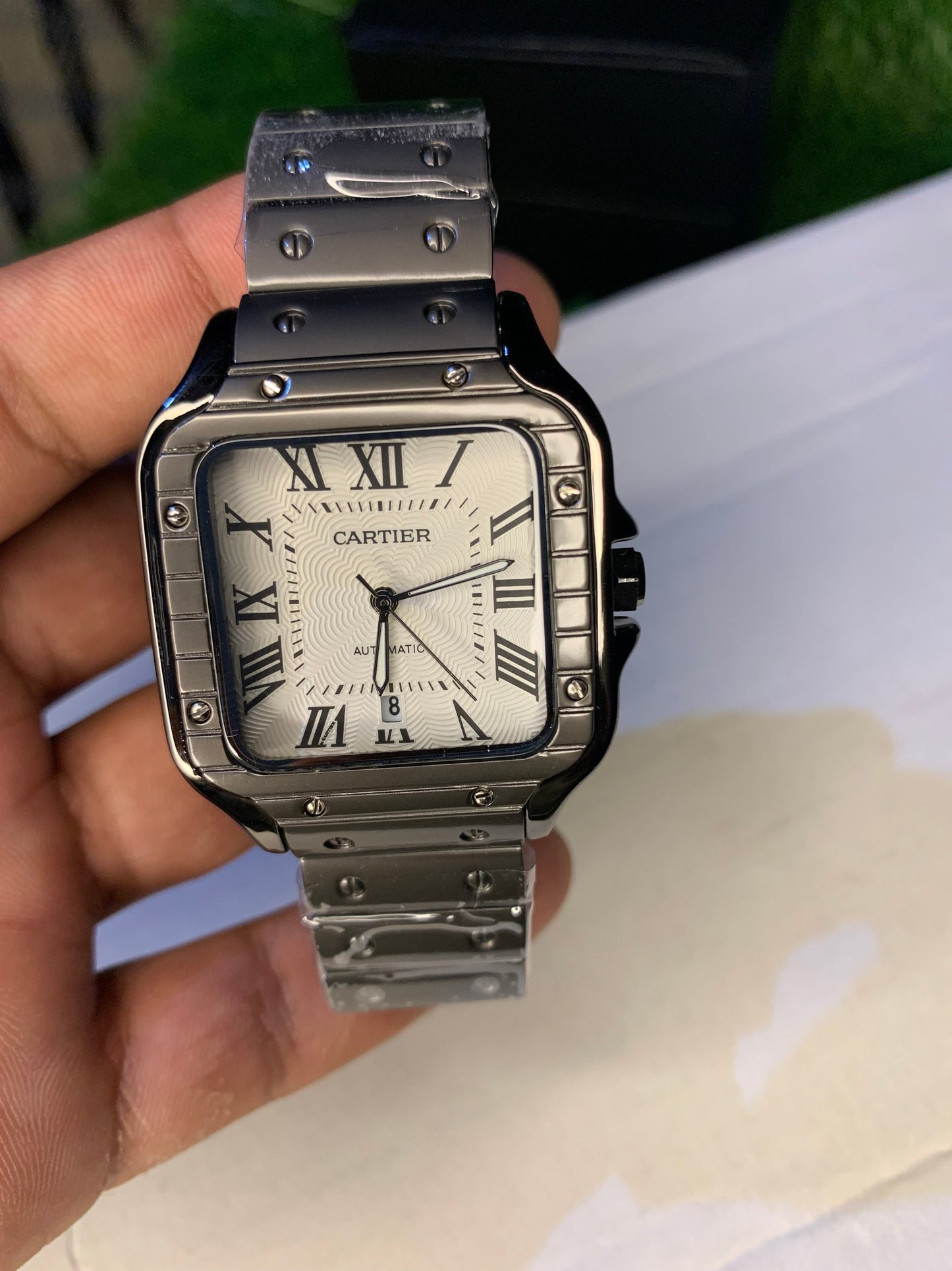 Cartier luxury watch with a square black stainless steel case, white textured dial, and bold Roman numeral markers. Features a sophisticated black bracelet and classic elegance, perfect for those with refined taste