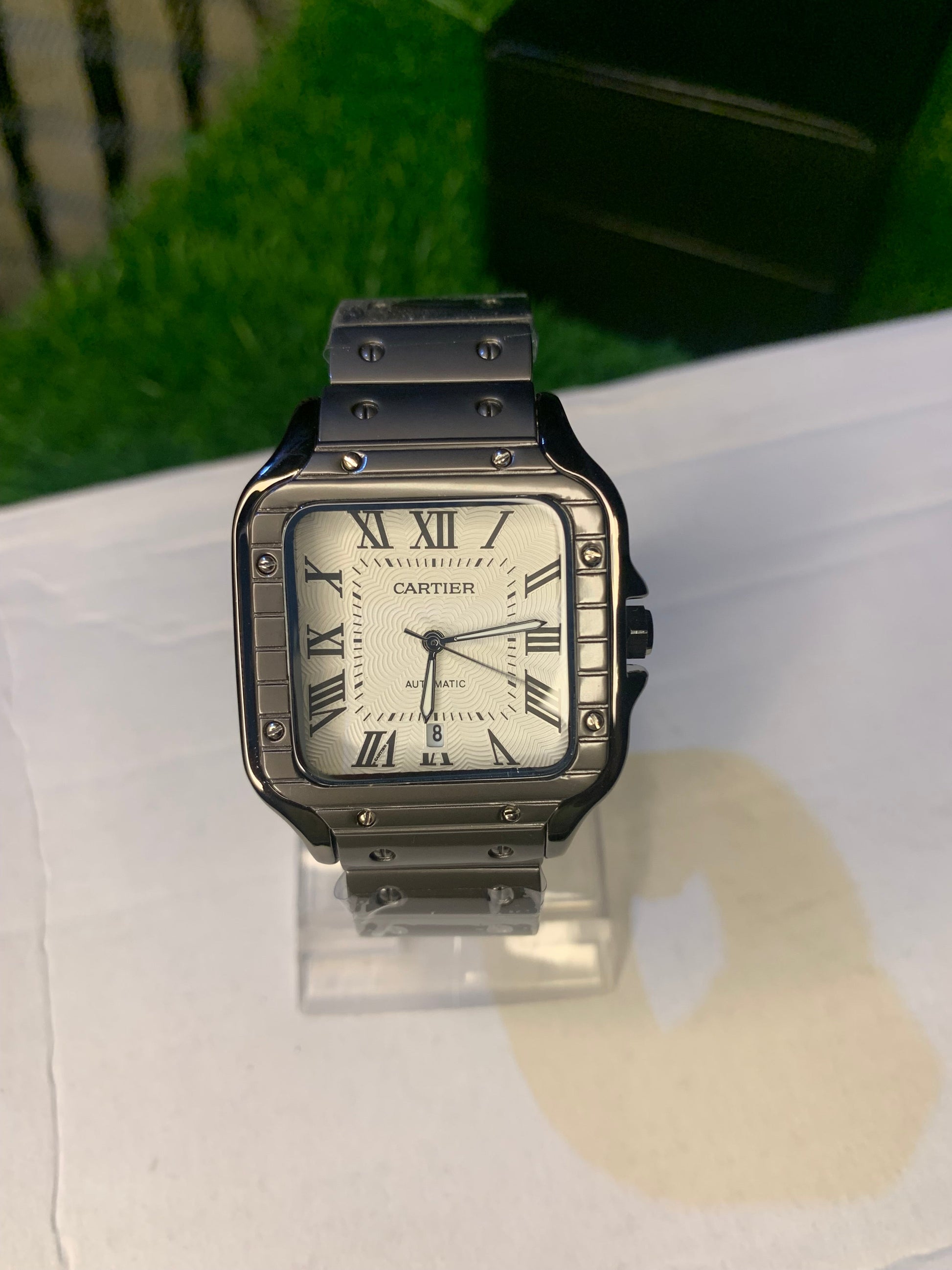 Cartier luxury watch with a square black stainless steel case, white textured dial, and bold Roman numeral markers. Features a sophisticated black bracelet and classic elegance, perfect for those with refined taste